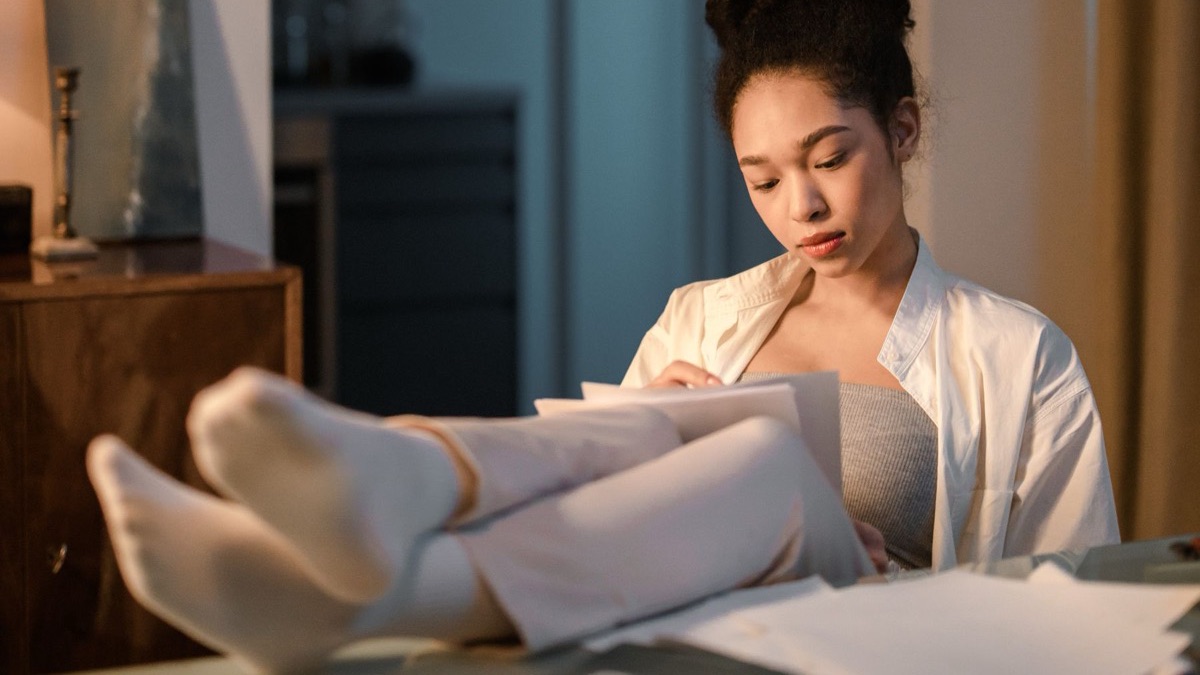 Person reviewing job loss paperwork at a kitchen table.